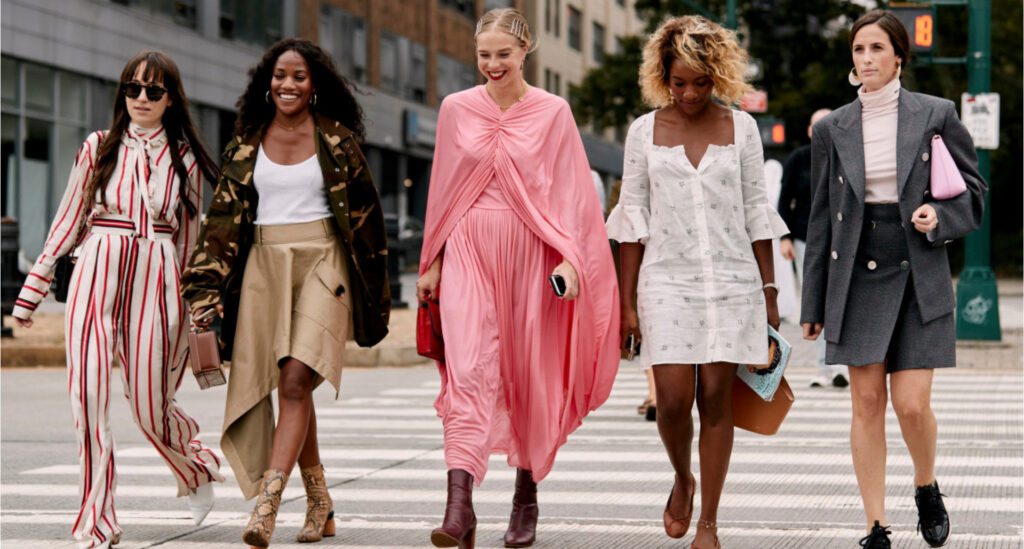 Foto de 5 mulheres atravessando uma faixa de pedestre, cada uma com um estilo de roupas diferente