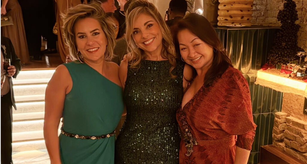 Foto da Silvia Scigliano com suas amigas, todas usam vestido de festa.