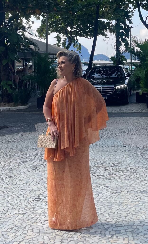 Foto da Silvia usando vestido leve laranja em festa de dia.
