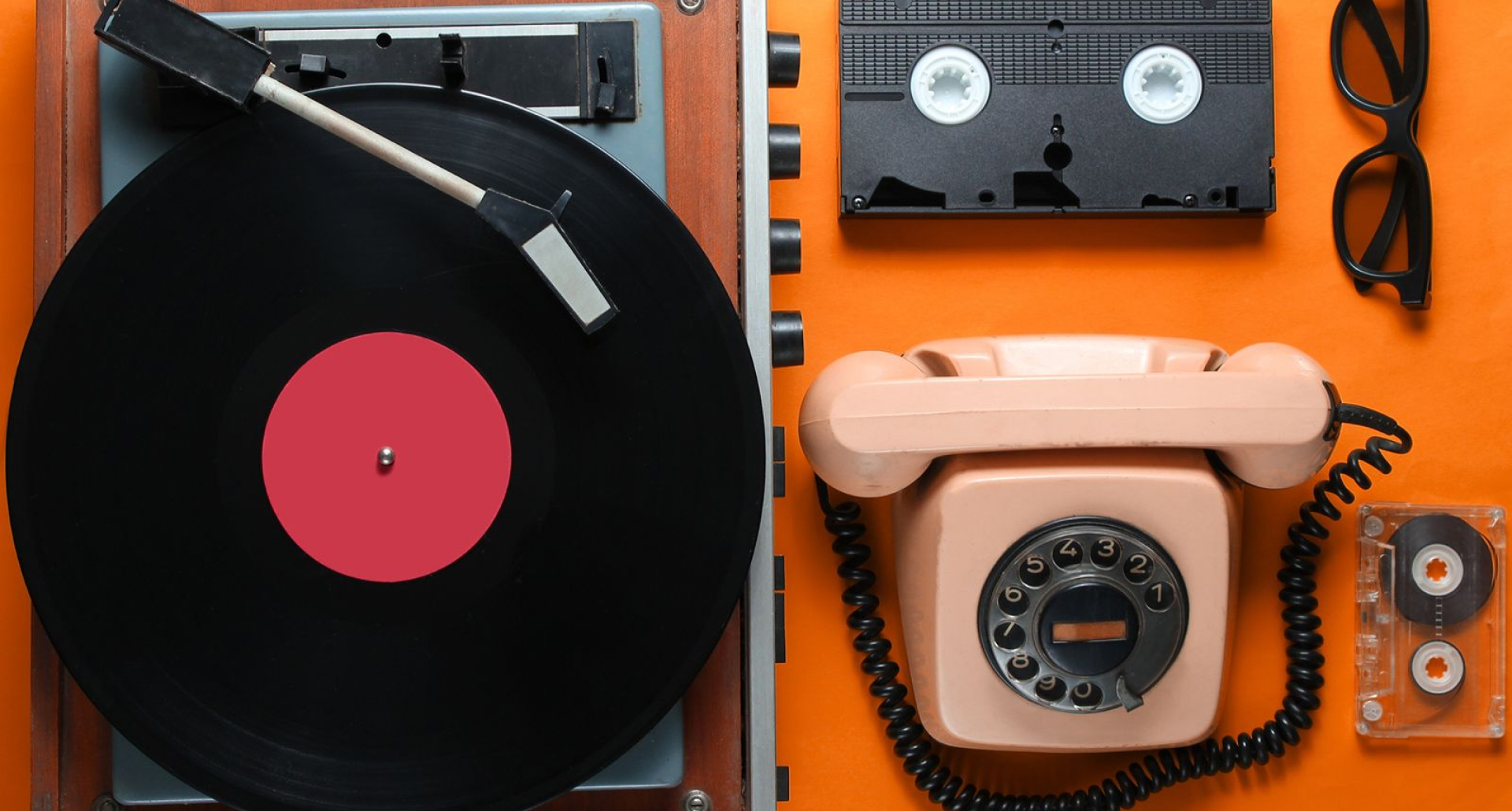 Foto de uma mesa com objetos antigos como telefone de fio, fita cassete e vitrola para demonstrar que as tendências de comportamento para 2026 são mais analógicas e nostáugicas.